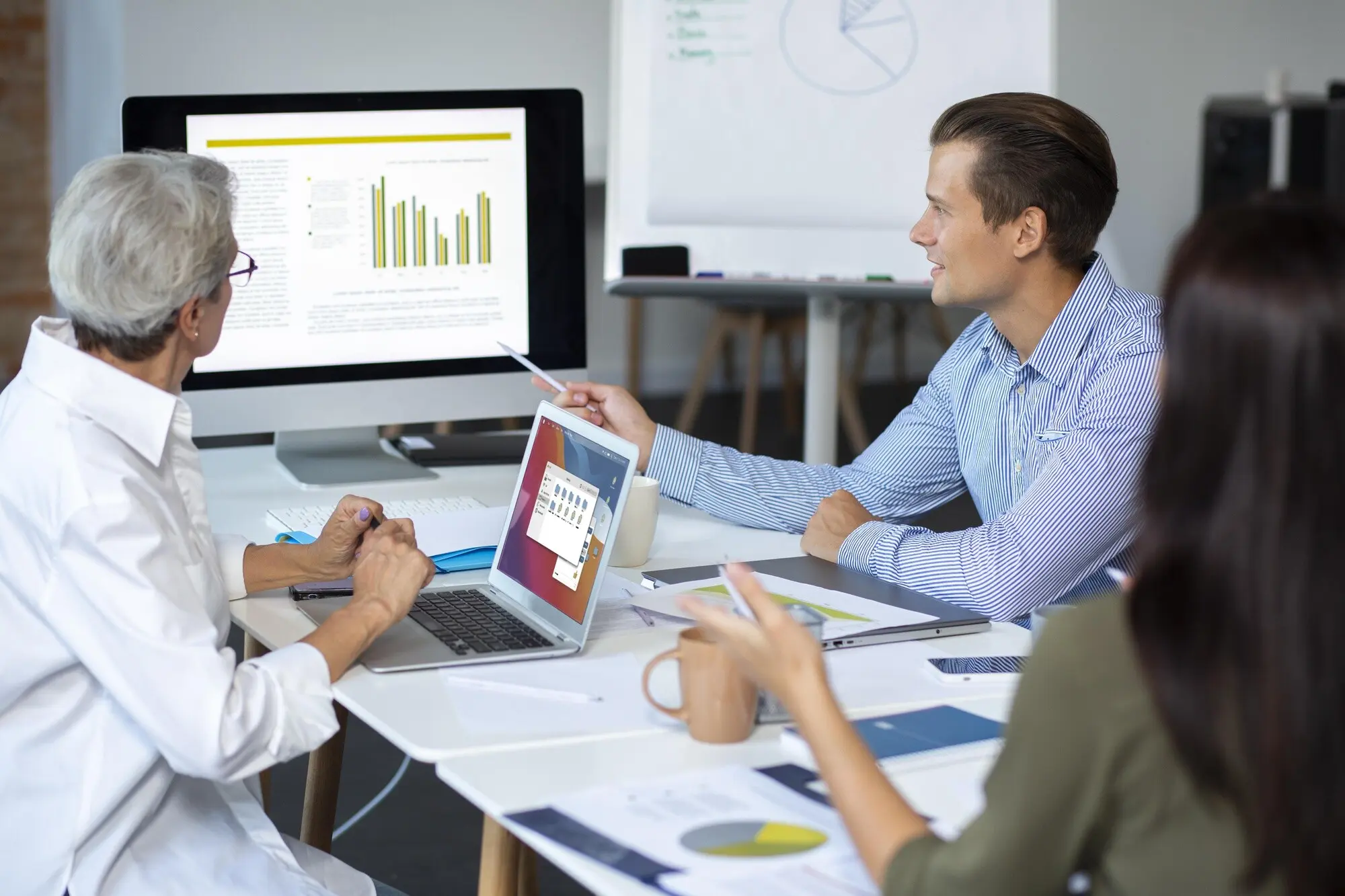 Personen, die während eines Meetings ein digitales Gerät nutzen